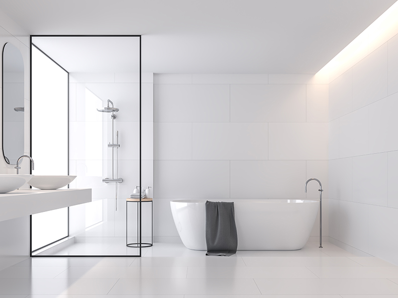 Minimale stijl witte badkamer. Badkamer met grote witte tegels aan de muur en op de vloer. Glazen scheidingswand voor douche. De badkamer heeft grote ramen die natuurlijk licht doorgegeven in de ruimte.